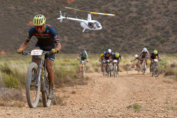 mountain-bike riders racing with helicopter in background